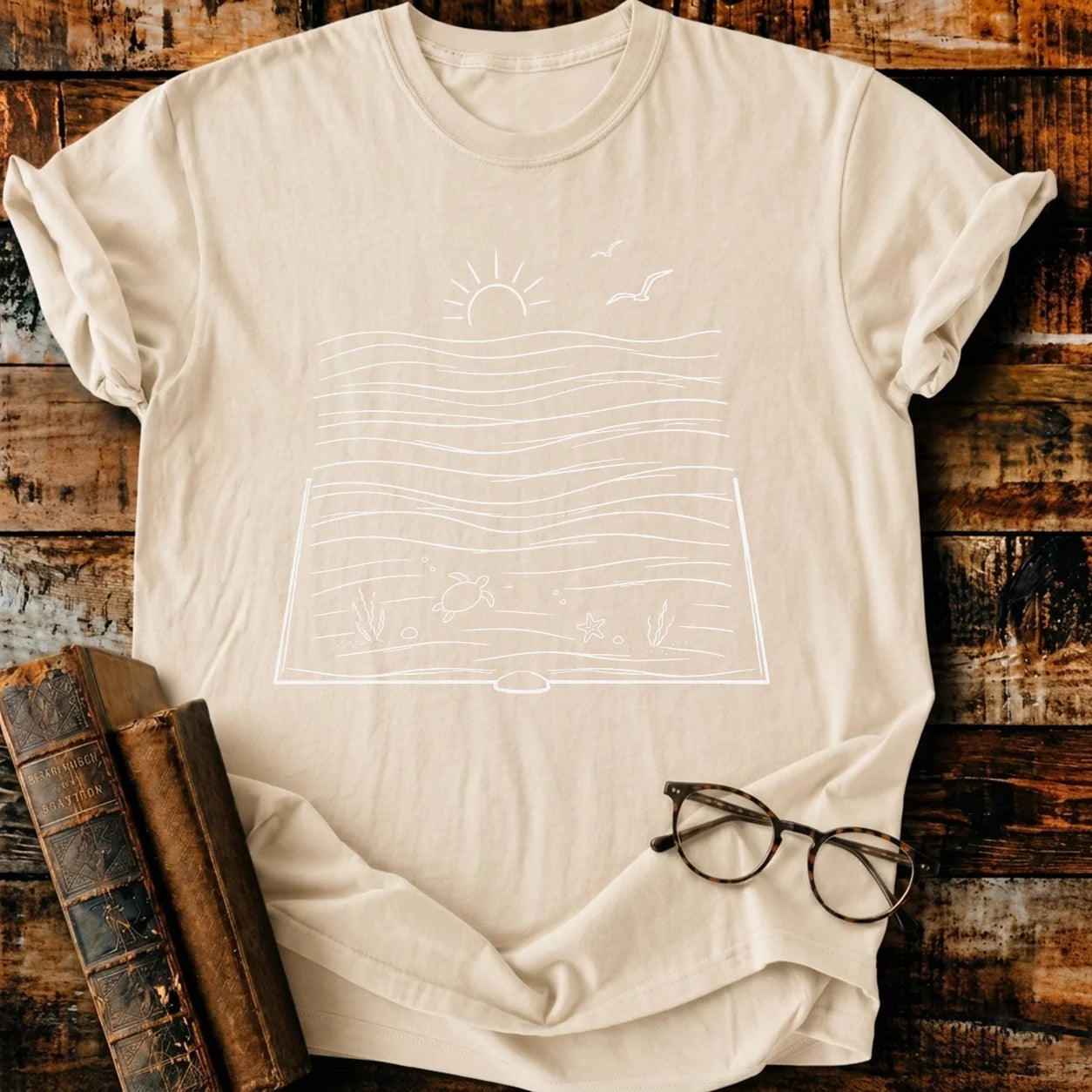 Relaxed fit, garment-dyed beige Comfort Colors t-shirt with a white bookish ocean graphic.