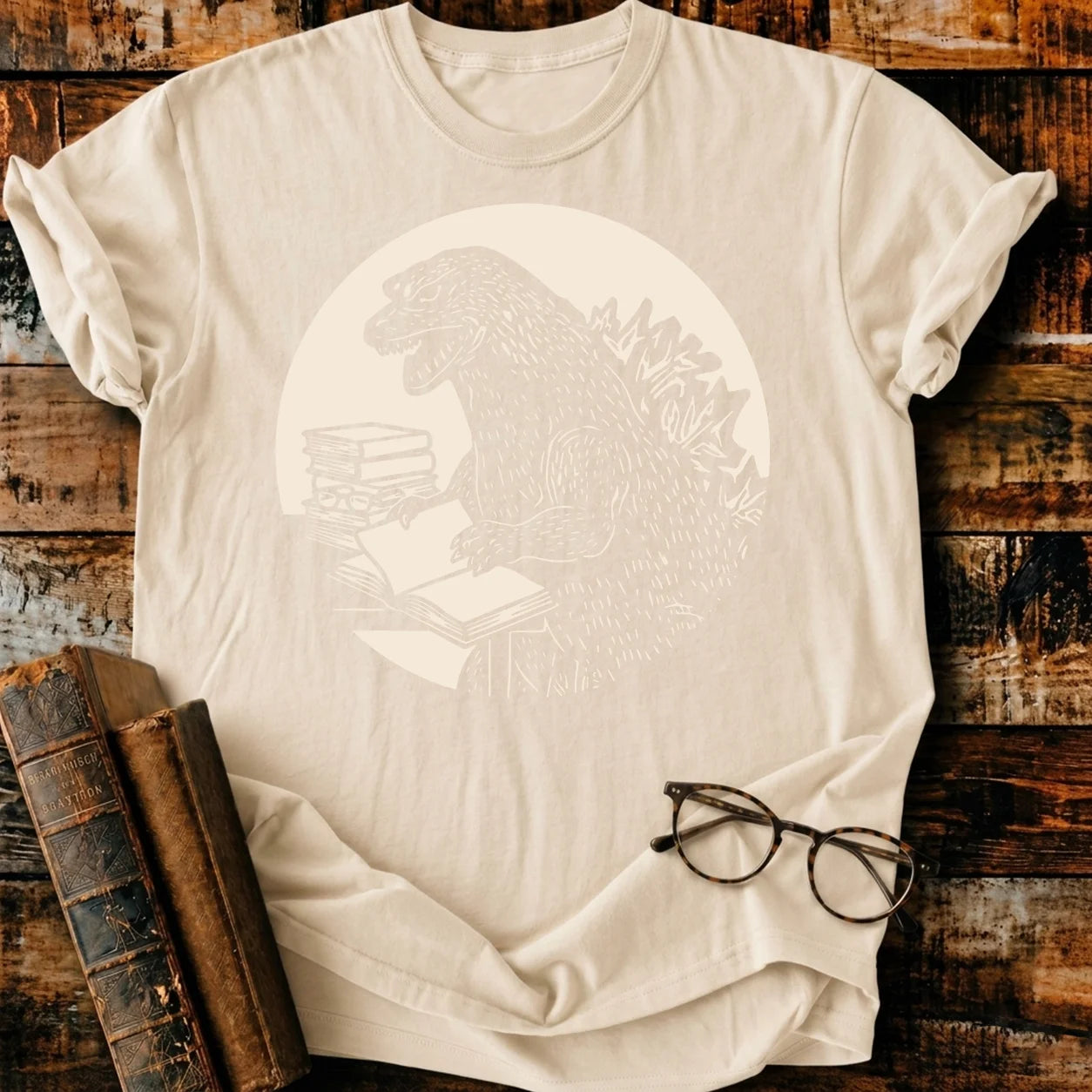 Readzilla T-shirt: Beige Comfort Colors 1717, relaxed fit, 100% cotton, with Godzilla reading books graphic.
