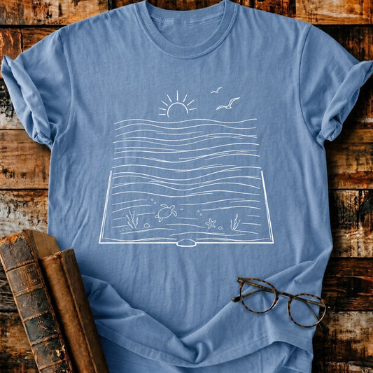 Relaxed fit Comfort Colors blue t-shirt with a white bookish ocean graphic, old books, and glasses.